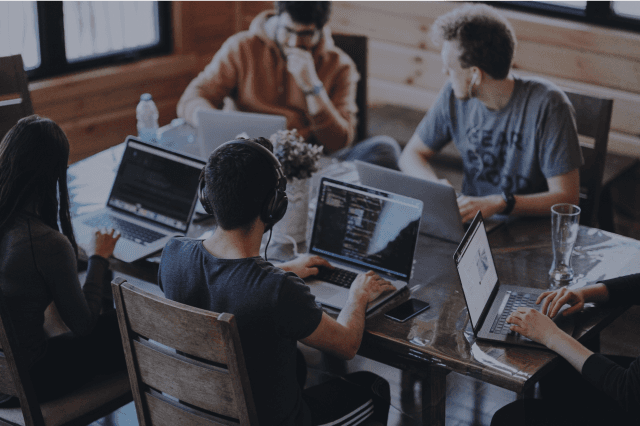 people sat at desks with laptops, working together