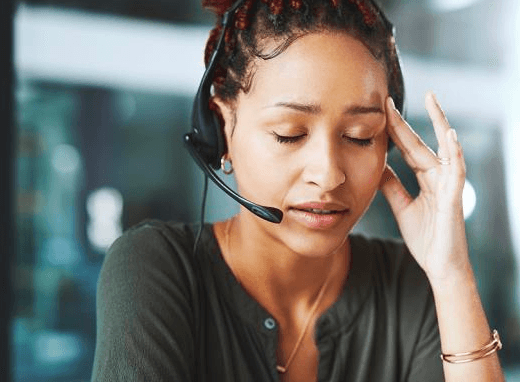 Person wearing headset looking stressed holding their head